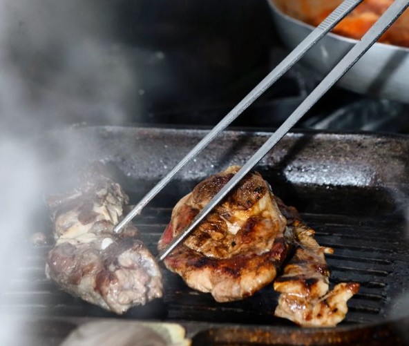 Grilled meat turned with tongs
