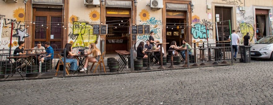 Outdoor tables on a San Lorenzo street, with murals on the buildings